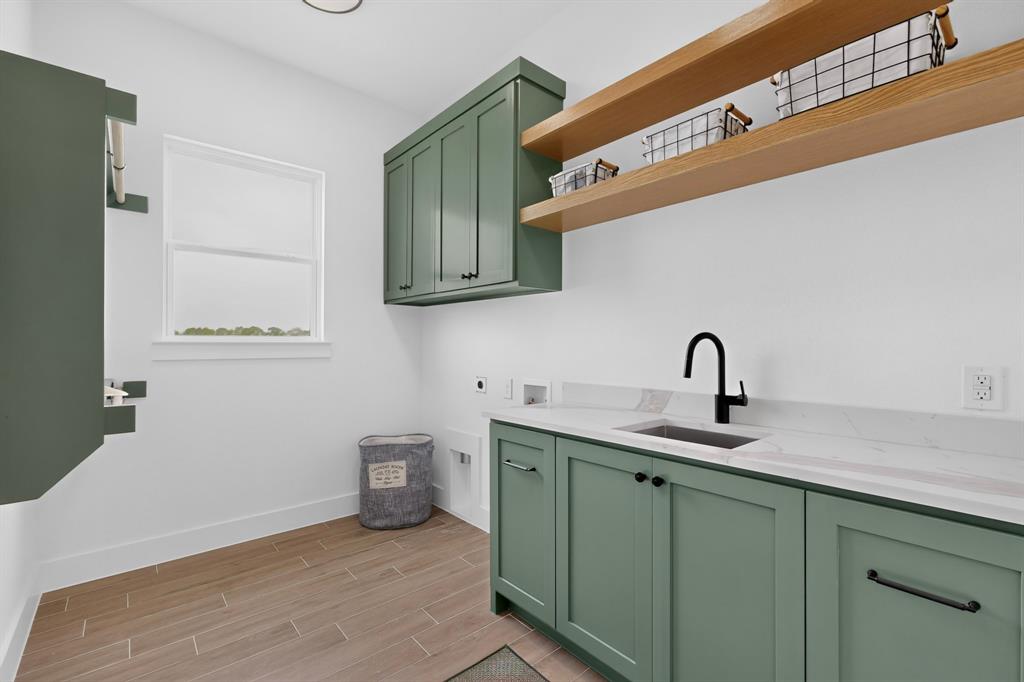 5410 Sunset Road Caddo Mills, TX 75135 - Photo 36 of 40 Laundry room with sage green cabinetry, a black matte faucet, light-toned countertop, and wood-finish flooring