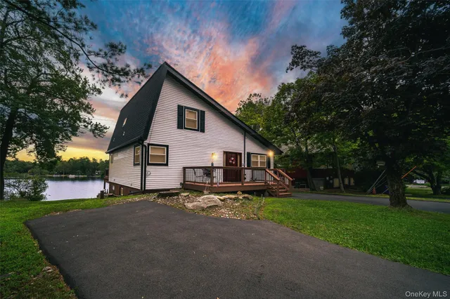 a view of a house with a yard and large trees