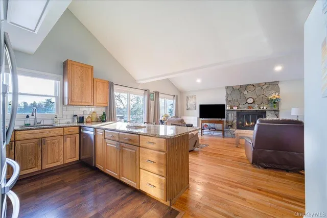 a living room with stainless steel appliances granite countertop furniture wooden floor and a kitchen view