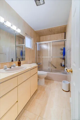 a bathroom with a granite countertop sink a toilet a mirror and bathtub