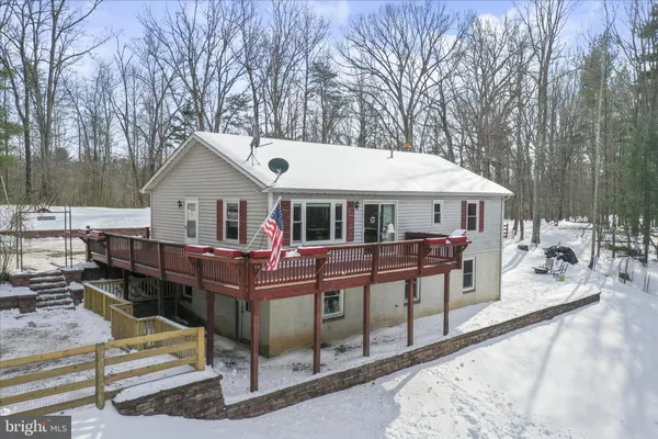 a view of a house with a wooden deck and a wooden fence