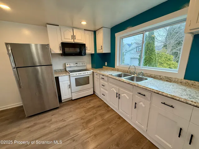 a kitchen with granite countertop a refrigerator a sink a stove a microwave and island