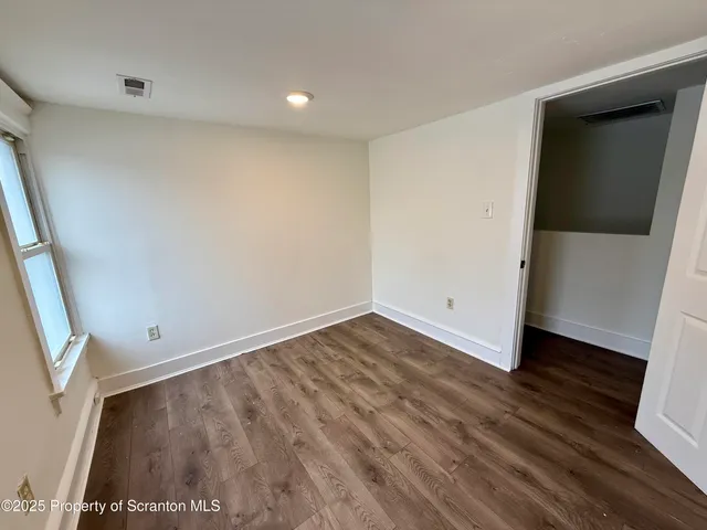 an empty room with wooden floor and entrance
