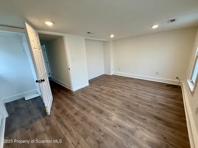 an empty room with wooden floor and entrance