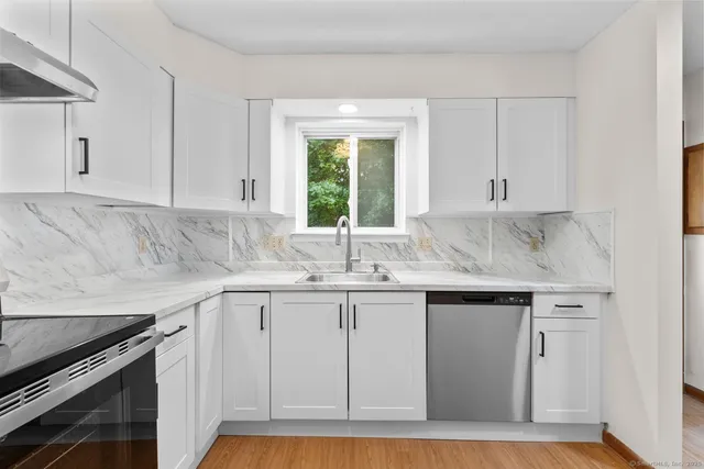 a kitchen with granite countertop white cabinets and a sink