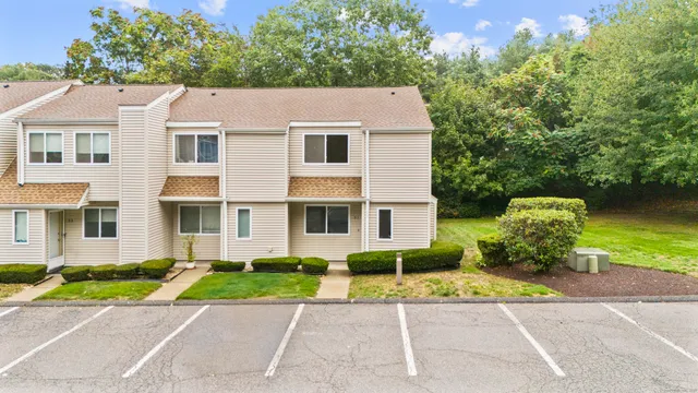 a view of a white house with a large trees plants and next to a yard