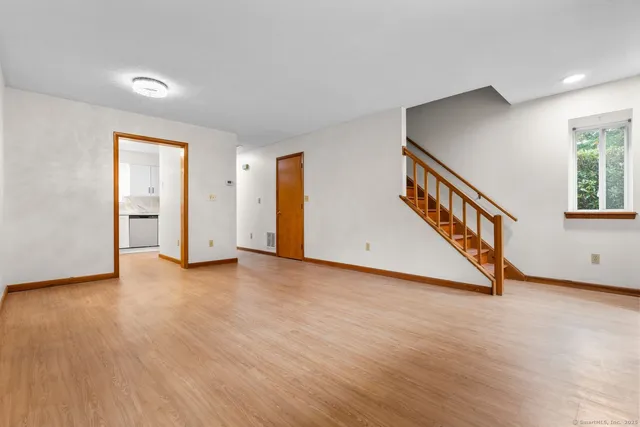 a view of an empty room with wooden floor and windows