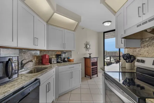 a kitchen with stainless steel appliances granite countertop a sink a stove and cabinets