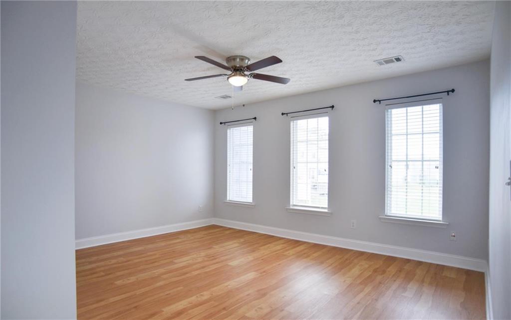 6616 Splashwater Drive Flowery Branch, GA 30542 - Photo 17 of 33 an empty room with wooden floor windows and fan