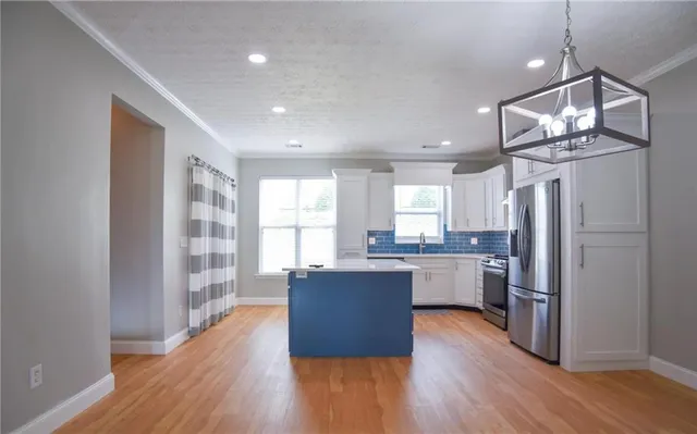 a kitchen with stainless steel appliances granite countertop a refrigerator a sink dishwasher a stove and white countertops with wooden floor