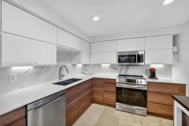 a kitchen with stainless steel appliances a stove a sink and white cabinets