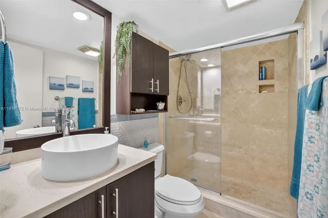 a bathroom with a sink a toilet a mirror and shower