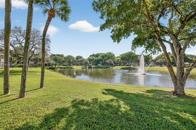 a view of a lake with a yard and large trees