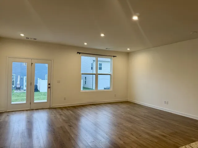 a view of an empty room with wooden floor and stairs