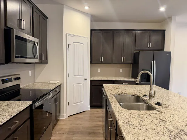 a kitchen with stainless steel appliances granite countertop a refrigerator and a stove top oven