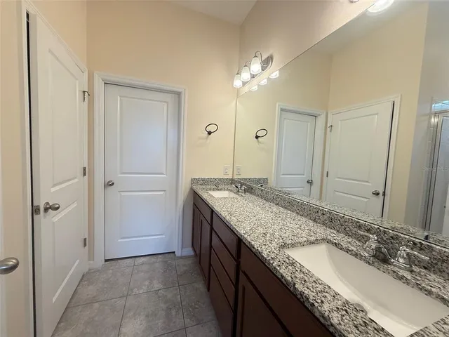 a bathroom with a granite countertop double vanity sink and mirror