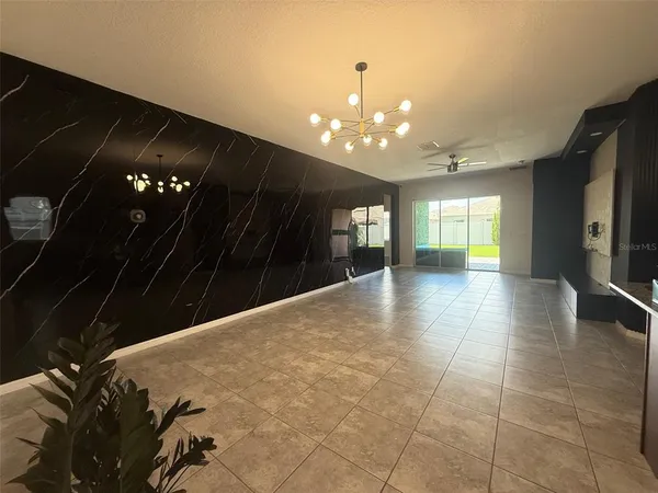 a view of an empty room with kitchen and window
