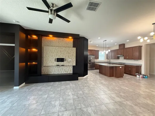 a kitchen with stainless steel appliances kitchen island granite countertop a refrigerator and a sink