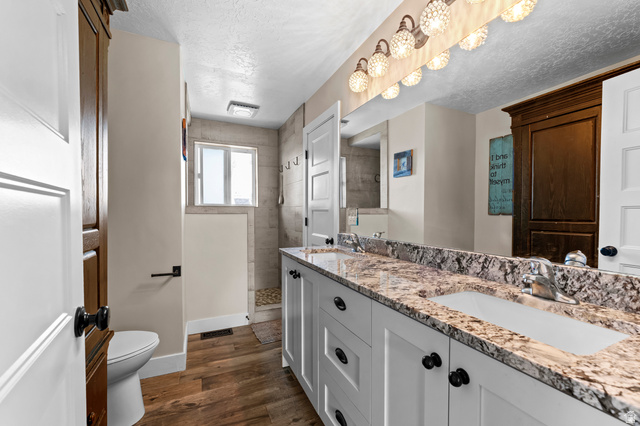 141 North 600 East Mapleton, UT 84664 - Photo 15 of 44 Bathroom with a walk in shower, double vanity, dark wood-style floors, and a textured ceiling
