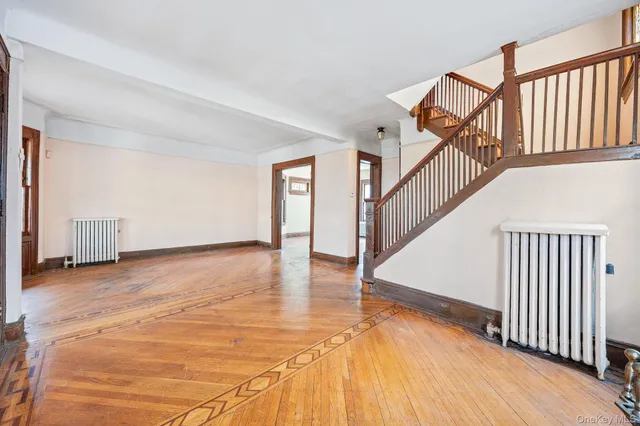a view of an empty room with wooden floor and stairs