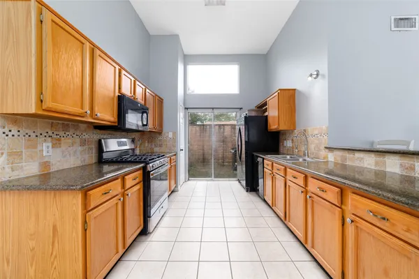 a large kitchen with stainless steel appliances granite countertop a stove a sink and a microwave