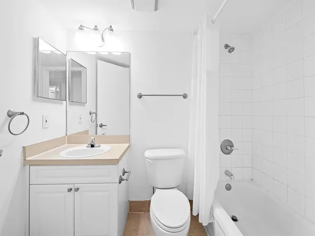 a bathroom with a toilet a sink a mirror a shower a vanity and window