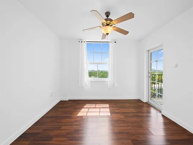 a view of empty room with wooden floor and fan