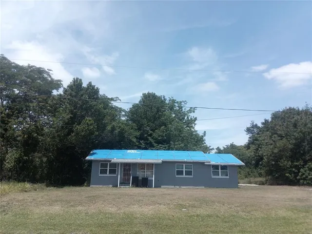 a front view of house with yard and trees in the background