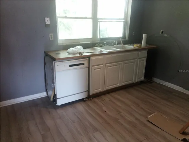 a kitchen with a sink cabinets wooden floor and a window