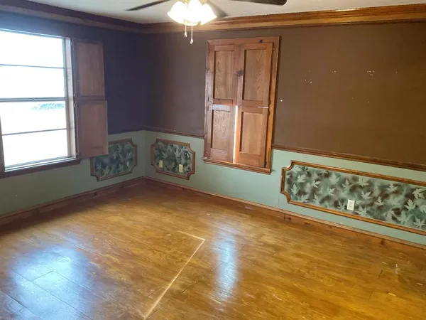 a view of an empty room with window and chandelier fan
