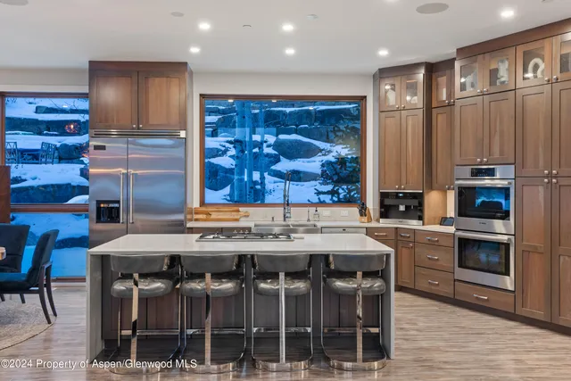 a kitchen with kitchen island granite countertop a table chairs sink and cabinets