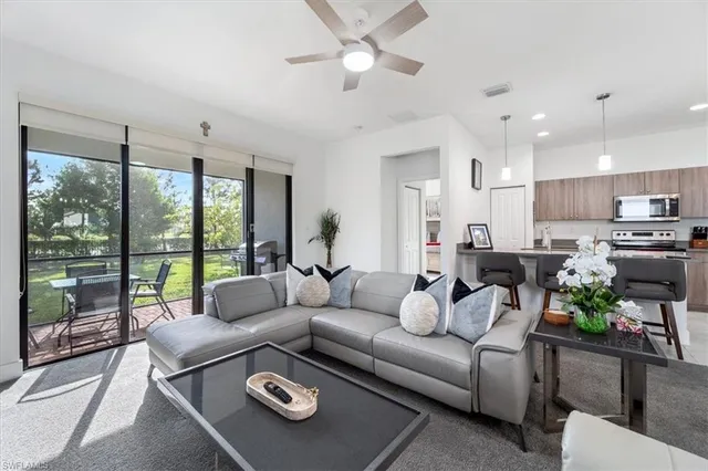 a living room with furniture and a large window with kitchen view