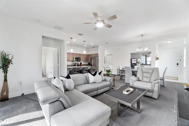 a living room with furniture kitchen view and a chandelier