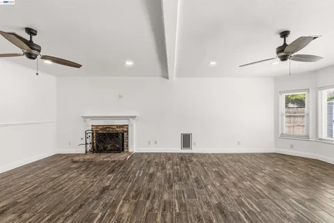 a view of empty room with wooden floor fireplace and a window