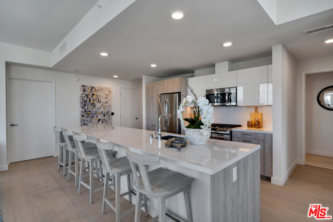 2801 Sunset Place, Unit 2009 Los Angeles, CA 90005 - Photo 3 of 18 a kitchen with stainless steel appliances a table chairs refrigerator and microwave