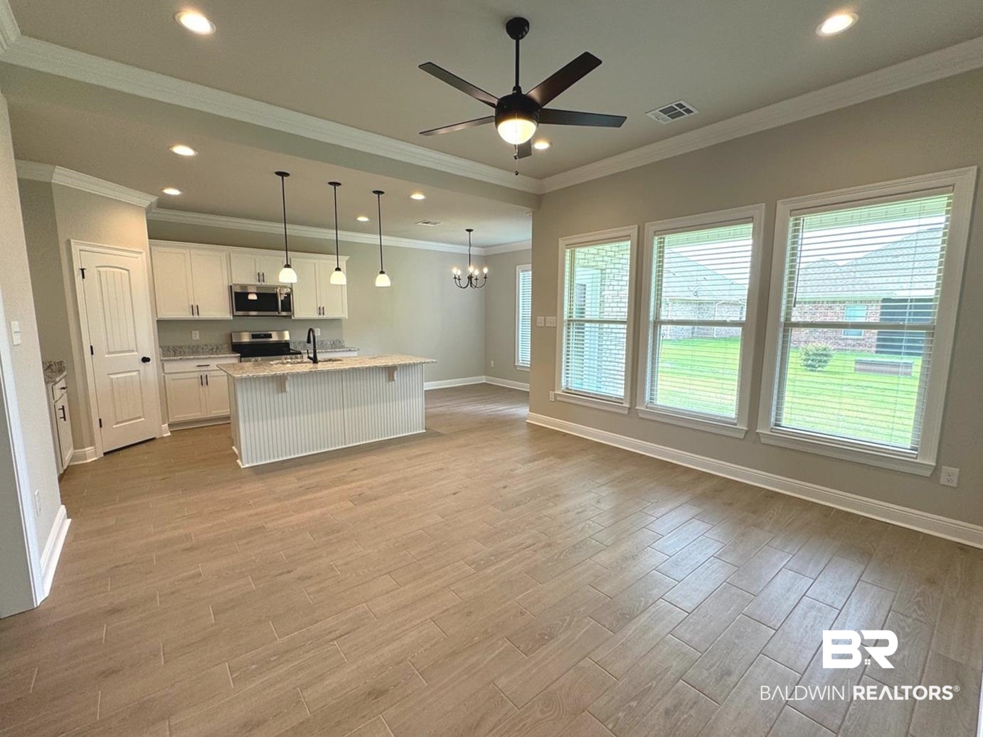904 Sumter Loop Foley, AL 36535 - Photo 2 of 10 Kitchen featuring stove, white cabinets, pendant lighting, a kitchen island with sink, and crown molding