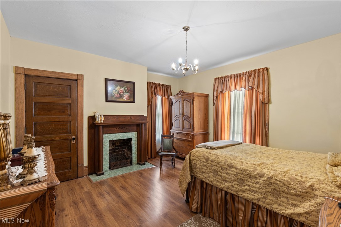 1011 Parriott Avenue Moundsville, WV 26041 - Photo 23 of 44 Bedroom with a fireplace with flush hearth, dark wood-style flooring, and a chandelier