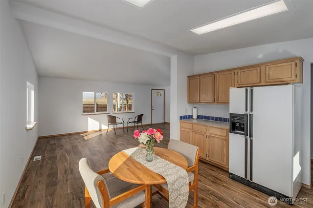 a kitchen with a refrigerator a stove top oven and a dining table with wooden floor