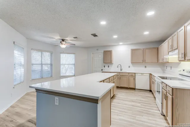 a large white kitchen with wooden floors and stainless steel appliances