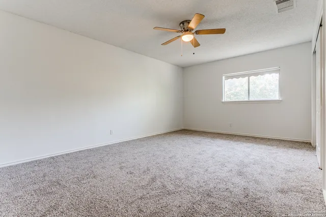 an empty room with a window and a ceiling fan
