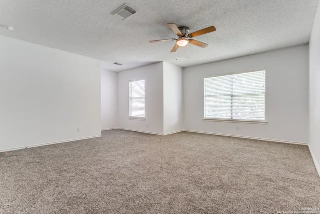 an empty room with windows and ceiling fan