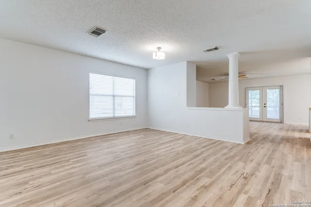 an empty room with wooden floor and windows