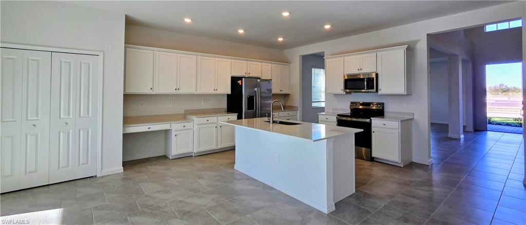 13329 Turnleaf Boulevard Punta Gorda, FL 33955 - Photo 7 of 23 Kitchen with appliances with stainless steel finishes, white cabinetry, an island with sink, recessed lighting, and built in study area