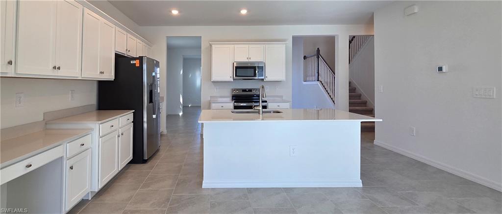 13329 Turnleaf Boulevard Punta Gorda, FL 33955 - Photo 8 of 23 Kitchen with white cabinets, a kitchen island with sink, appliances with stainless steel finishes, light stone counters, and recessed lighting
