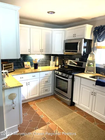 a kitchen with stainless steel appliances granite countertop a stove a sink and a microwave
