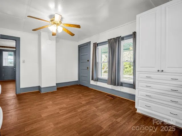 an empty room with wooden floor closet and windows