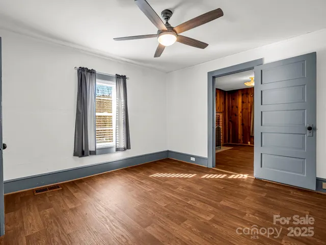 an empty room with wooden floor closet and windows