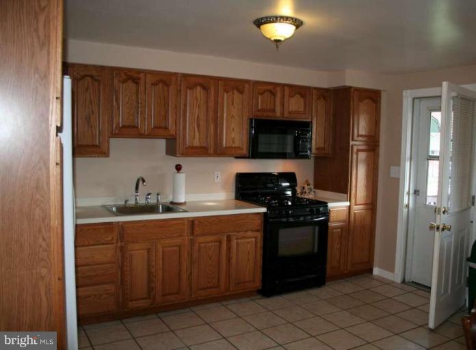 7811 Harold Road Dundalk, MD 21222 - Photo 4 of 10 a kitchen with stainless steel appliances granite countertop a stove a sink and a refrigerator