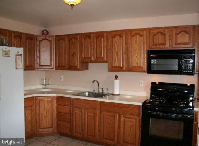 7811 Harold Road Dundalk, MD 21222 - Photo 8 of 10 a kitchen with stainless steel appliances granite countertop a sink stove and microwave