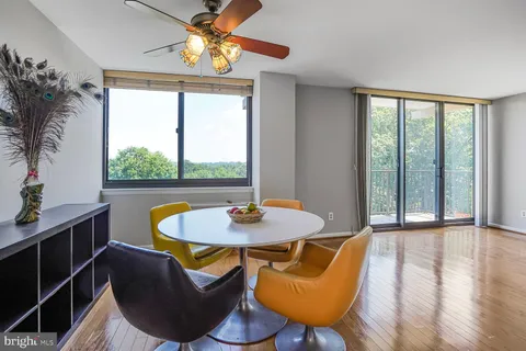 a dining room with furniture a large window and wooden floor